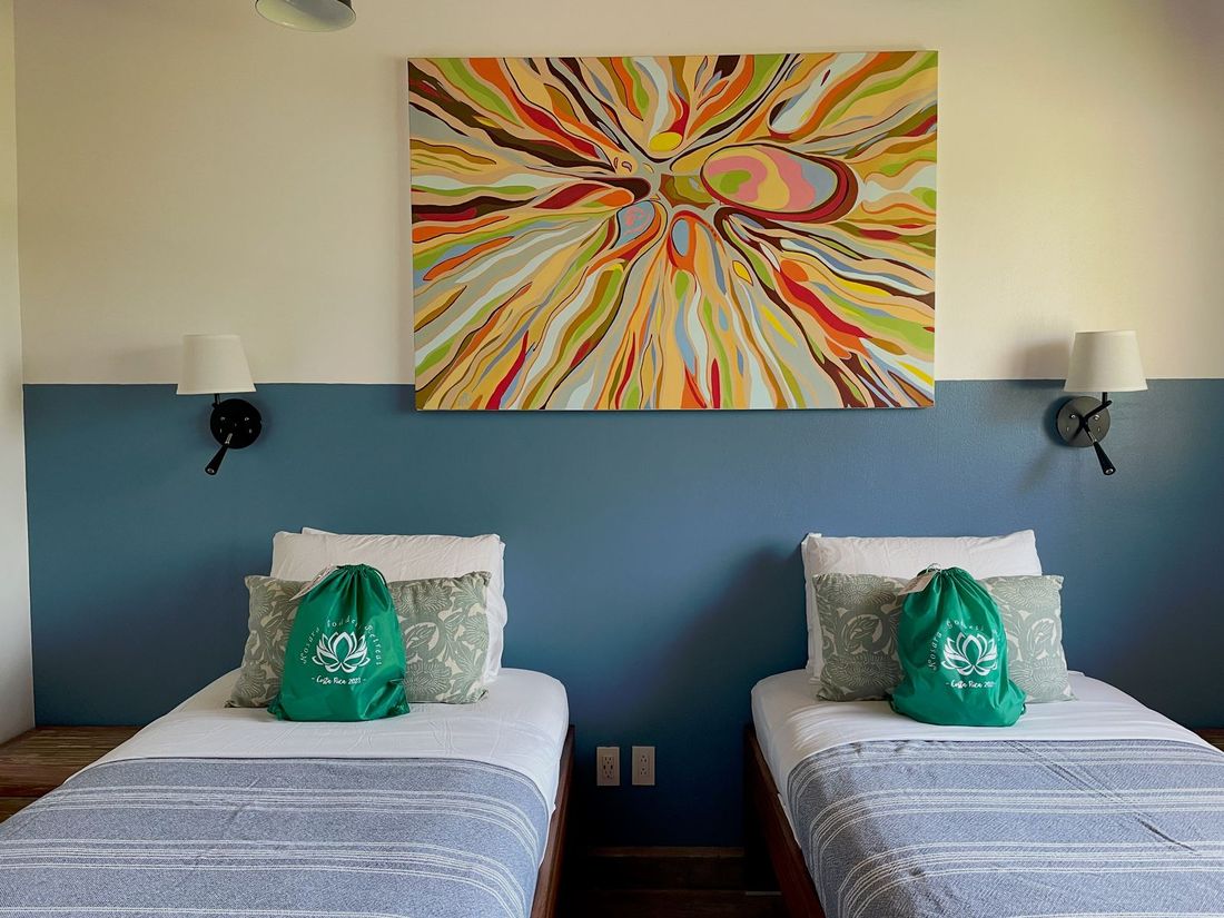 One of the five ensuite bedrooms, twin beds beneath a painted canvas