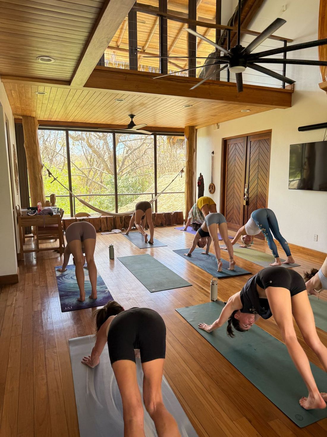 A group flowing through a yoga practice in the villa&rsquo;s timber-framed great room